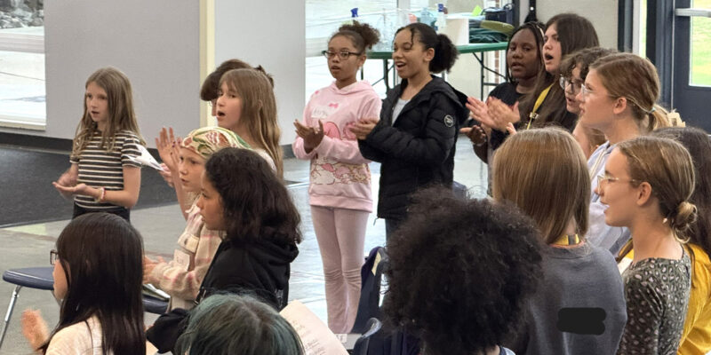 Middle school children singing at choir rehearsal.